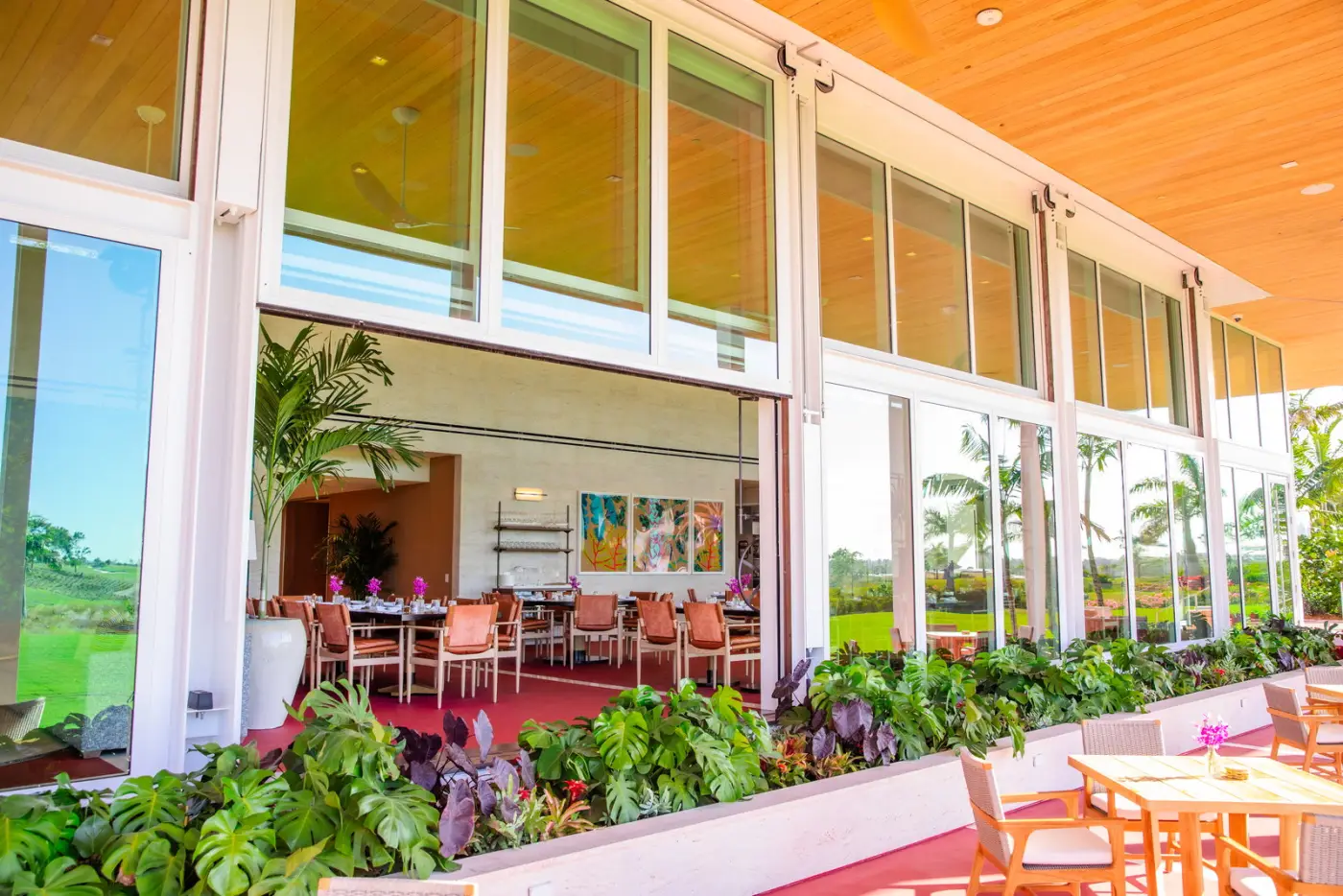 A dining room opening onto a terrace through a tall glass window wall with its panels raised
