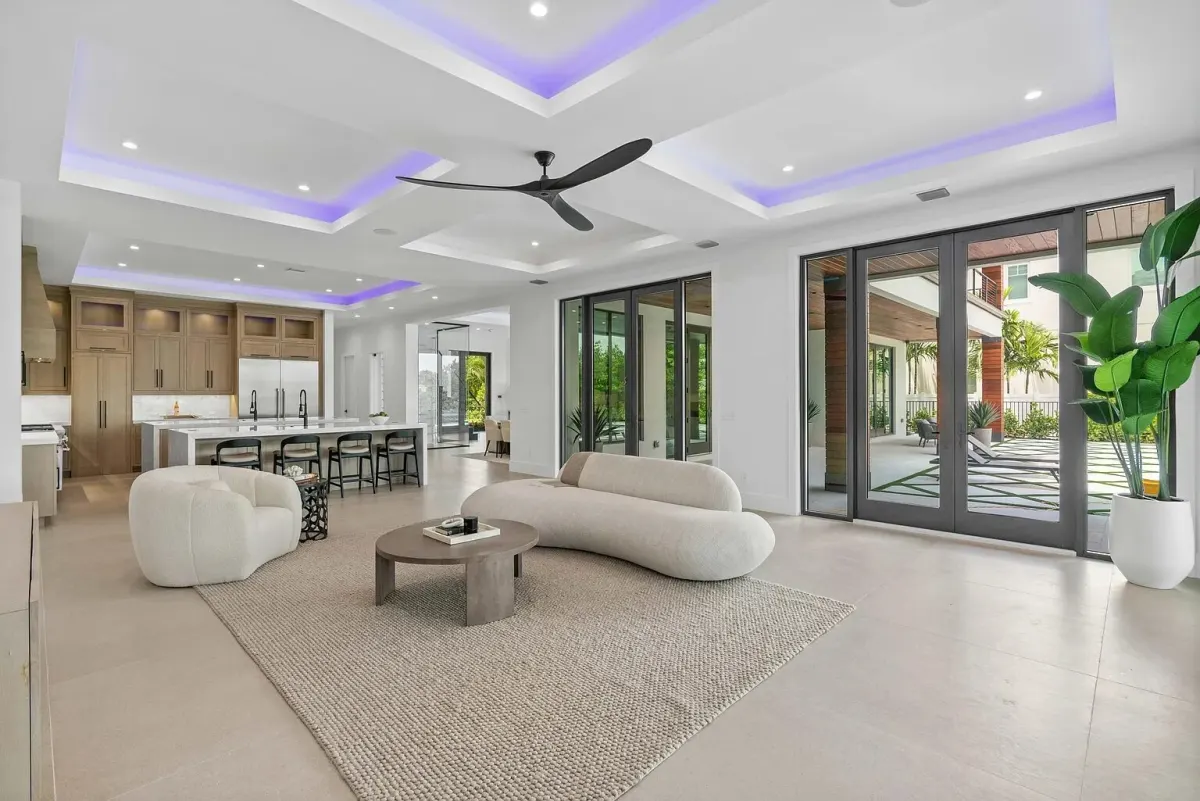 A living room with tall glass sliding doors opening to a pool deck